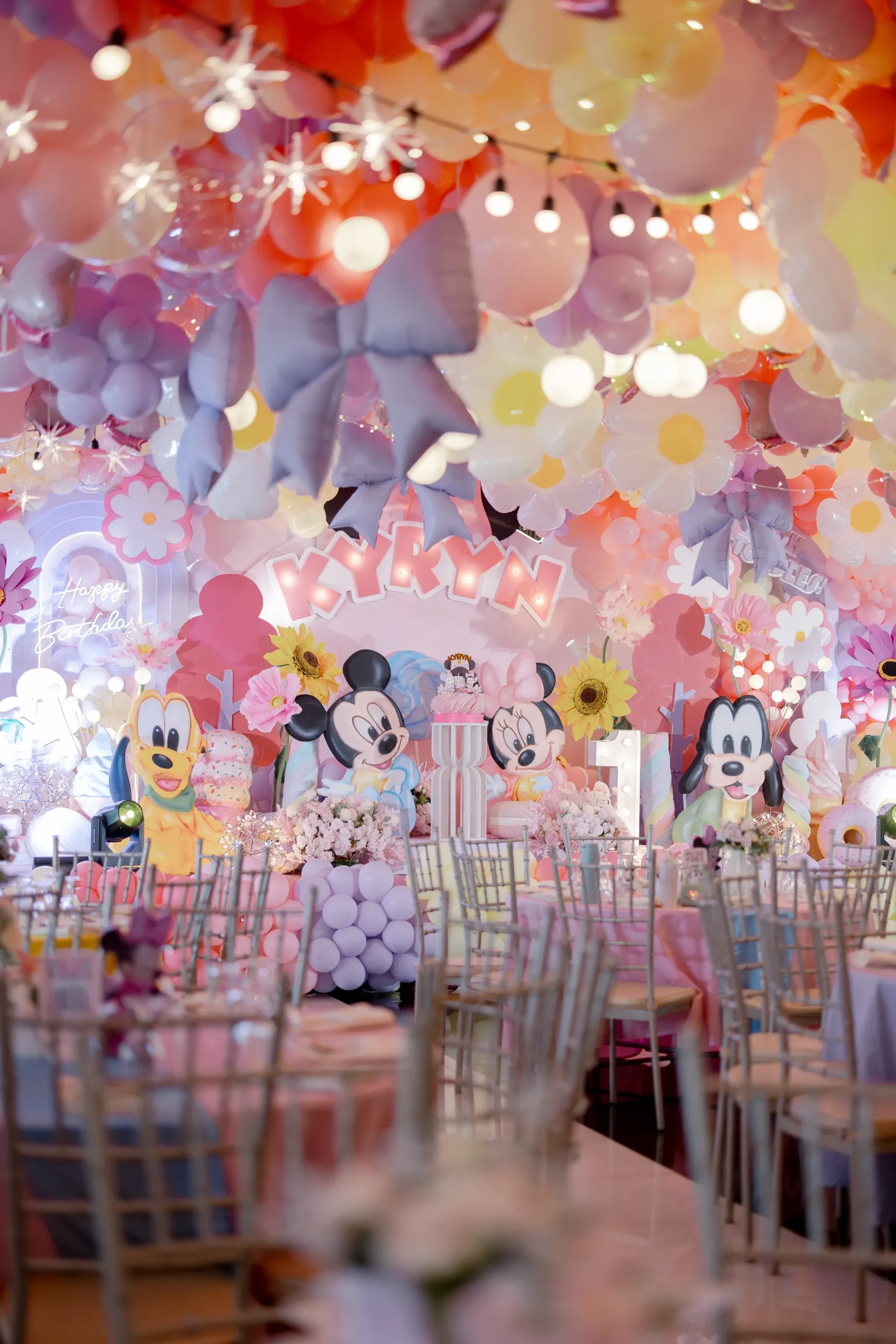 Minnie Mouse birthday backdrop for Kyryn with oversized daisies, pastel balloons, bows and Disney character decorations
