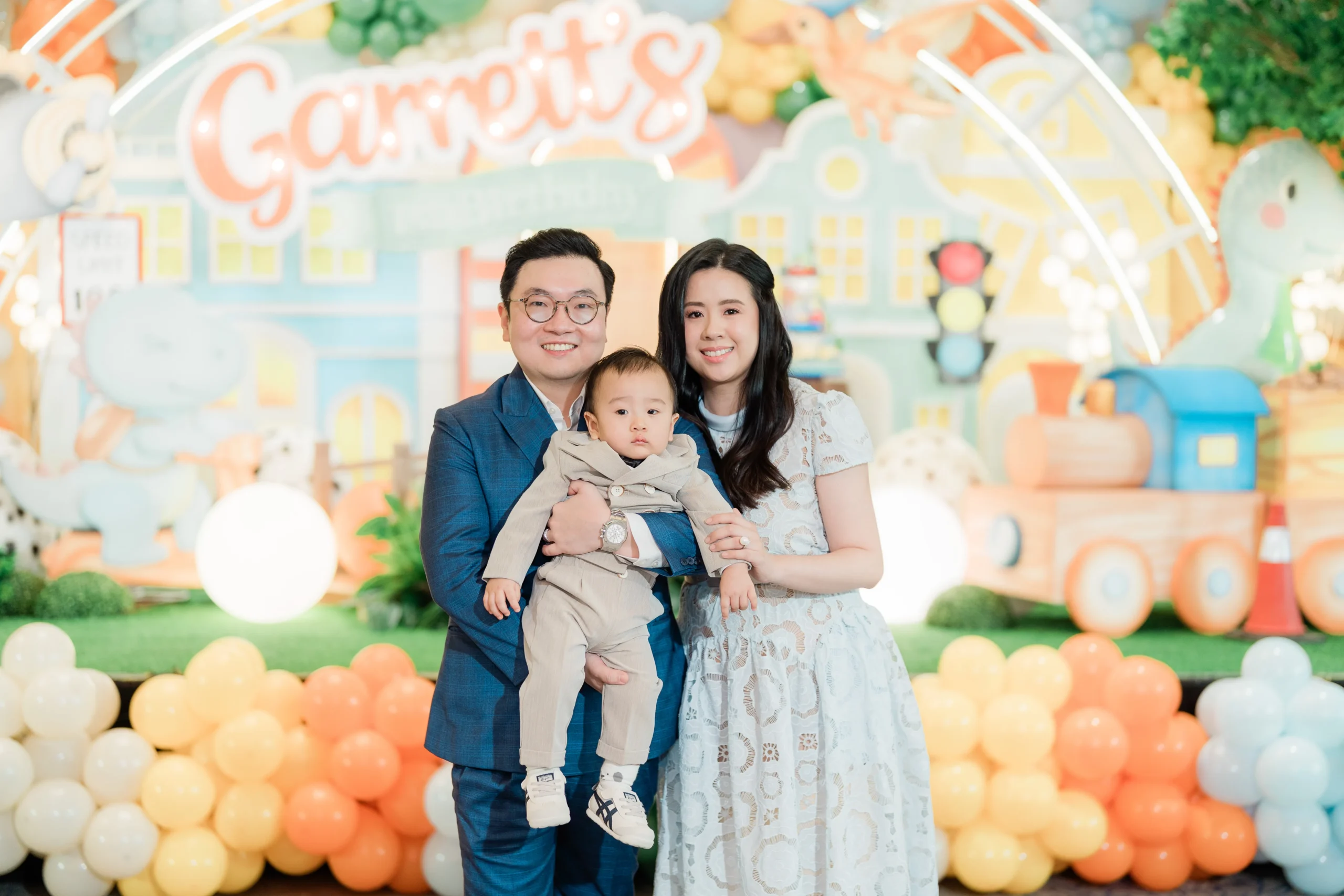 Pastel dinosaur birthday stage with balloons, trees and city decorations