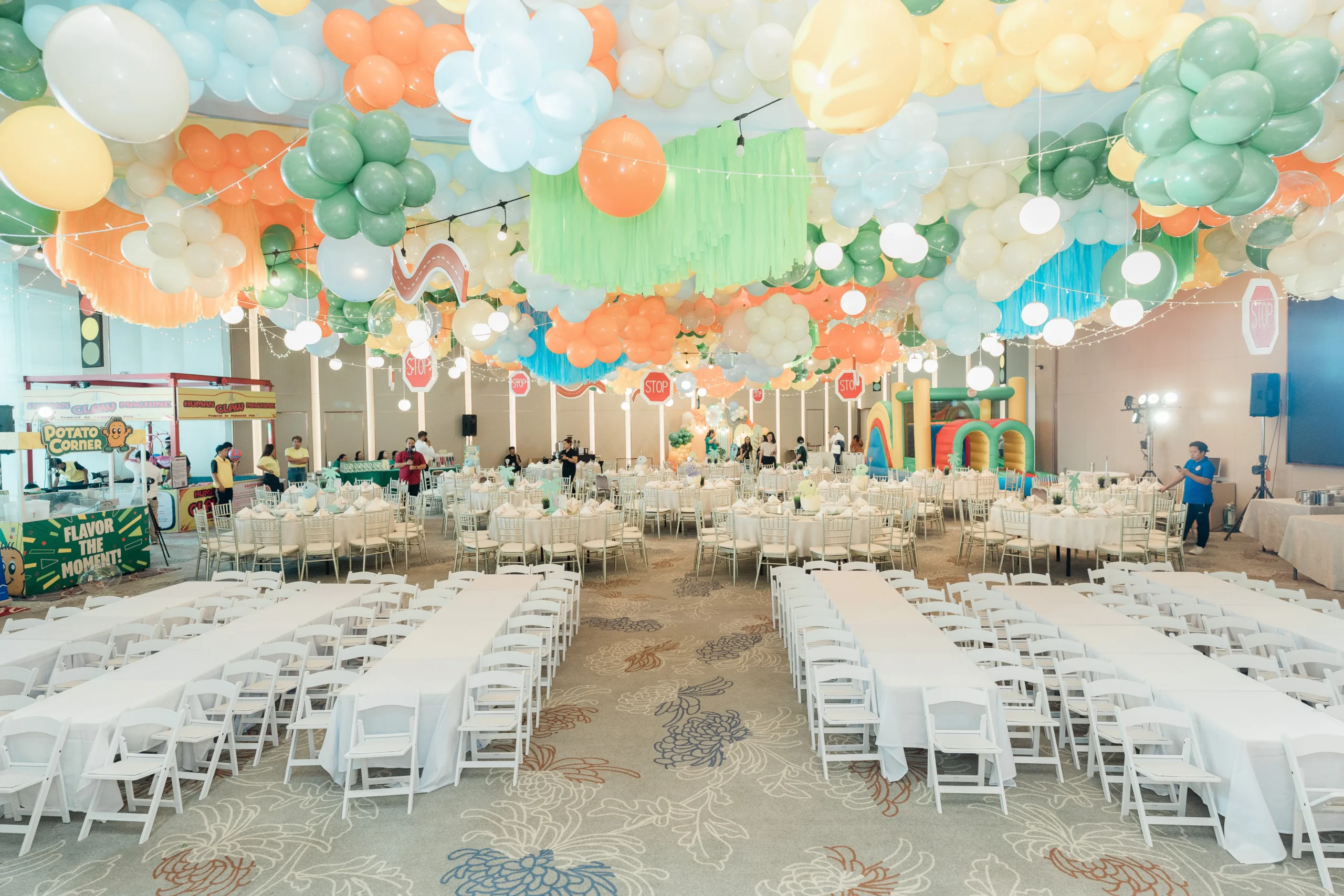 Pastel dinosaur birthday stage with balloons, trees and city decorations